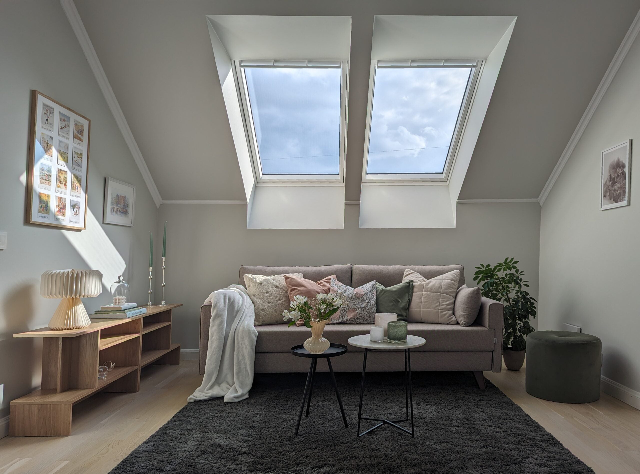 Homestyling av allrum, efterbild med soffa, tavlor, sittpuff, takfönster och bord